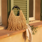Natural raffia fringe crescent bag styled in a warm Mediterranean setting