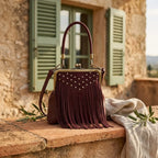 Burgundy red fringe clutch bag styled in a warm Mediterranean setting