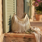 Gold slouchy fringe bag styled in a warm Mediterranean setting