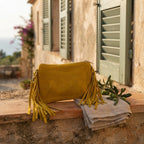 Green small suede fringe bag styled in a warm Mediterranean setting