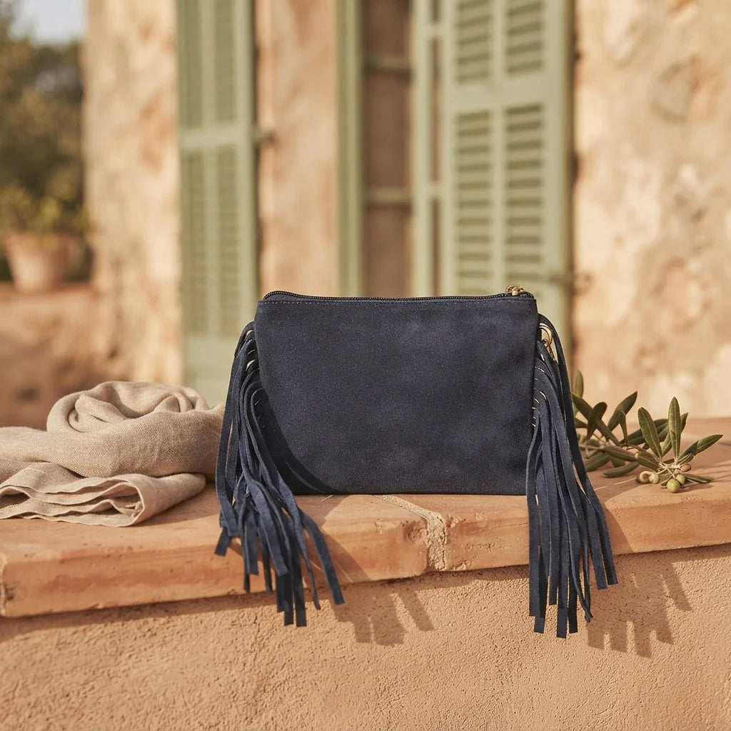 Navy small suede fringe bag styled in a warm Mediterranean setting