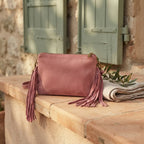 Pink small suede fringe bag styled in a warm Mediterranean setting
