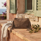 Taupe small suede fringe bag styled in a warm Mediterranean setting