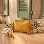 Yellow small suede fringe bag styled in a warm Mediterranean setting