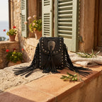 Black studded fringe crossbody bag styled in a warm Mediterranean setting