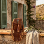 Brown studded fringe crossbody bag styled in a warm Mediterranean setting