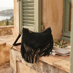 Black suede fringe clutch bag styled in a warm Mediterranean setting