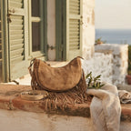 Camel suede fringe clutch bag styled in a warm Mediterranean setting