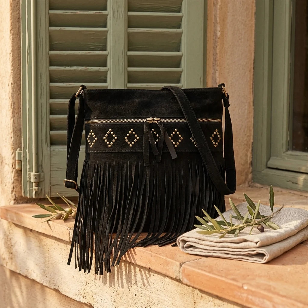 Black suede fringe messenger bag styled in a warm Mediterranean setting