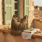 Khaki tassel fringe hobo bag styled in a warm Mediterranean setting