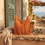 Orange tassel fringe hobo bag styled in a warm Mediterranean setting
