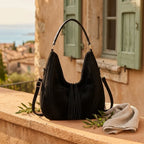 Black vegan fringe hobo bag styled in a warm Mediterranean setting