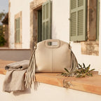 Cream white fringe shoulder bag styled in a warm Mediterranean setting