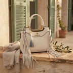 Ivory white fringe tote bag styled in a warm Mediterranean setting