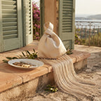 Beige wristlet fringe bag styled in a warm Mediterranean setting