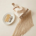 Beige wristlet fringe bag, three-quarter angle showing side depth